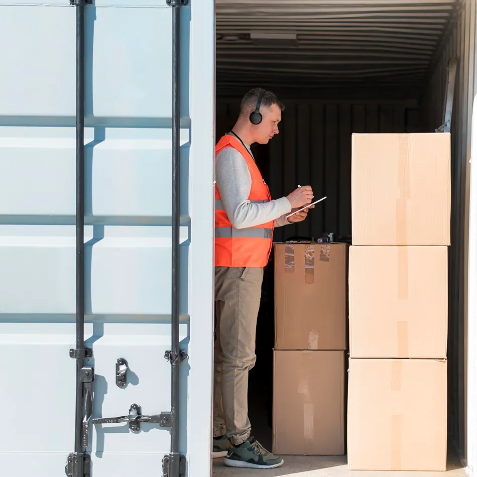 Transporte de mercancías en Valencia con operario revisando cajas en contenedor logístico